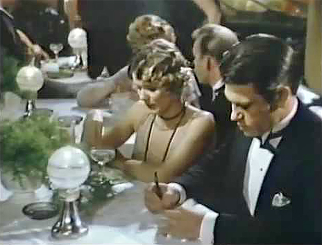 Een beeld uit de film. Hughes zit aan bij een gala-diner.