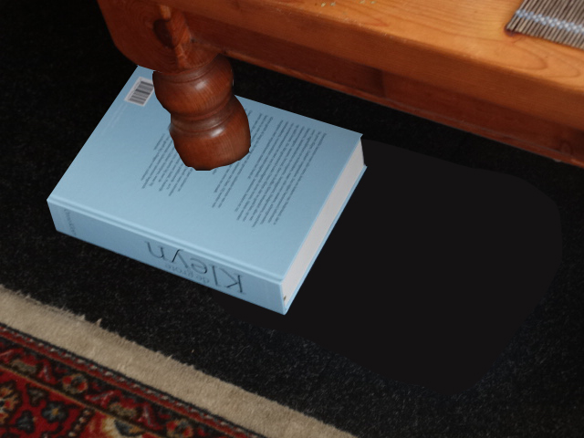 Het boek 'De grote Kleyn' onder een tafelpoot waar een stuk af is.