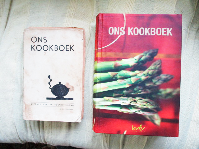 De kaft van Kookboek, met groene asperges op de nieuwere editie. Op de kaft van het oude exemplaar een tekening van een dampende pan.