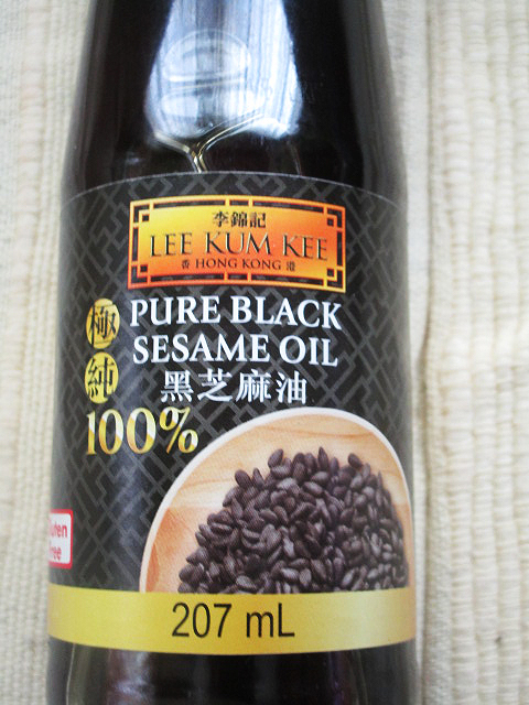Een flesje Chinese sesamolie, met daarop de tekst 'Pure black sesame oil'.
