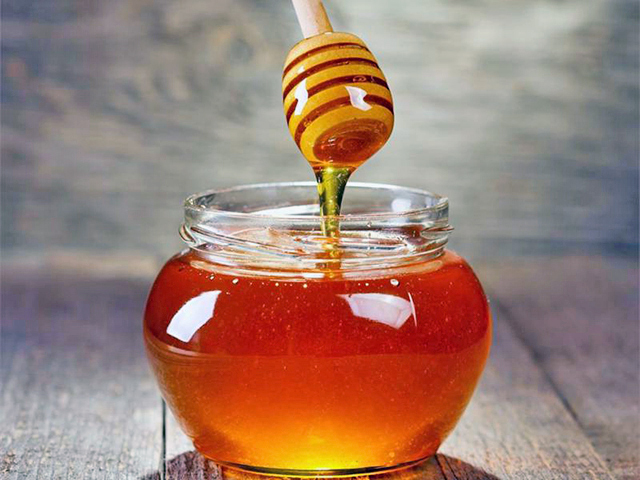 Een pot honing met een honey dipper.