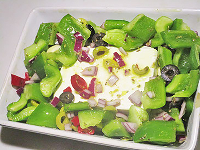 Feta met groenten eromheen, in een ovenschaal.