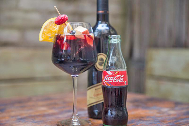 Een fles rode wijn weer, een blikje waarvan nu te zien is dat het cola is, en een glas kalimotxo.