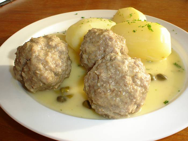 Een bord met gekookte aardappelen en Königsberger Klopse.