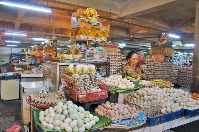 Een vrouw met verschillende soorten eieren op een markt in Indonesië.