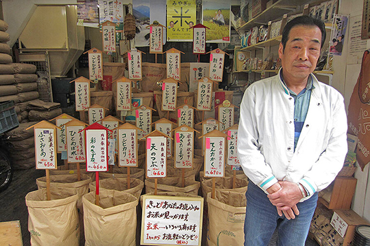 De eigenar van een japanse rijstwinkel voor zijn voorraad met enorm veel soorten rijst.