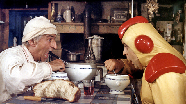 Een scène uit de film. Funes en het marmannetje zitten aan tafel en schrokken van de soep.