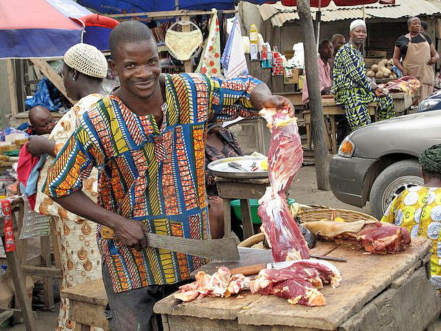Een vlees-verkoper hakt stukken vlees klein.