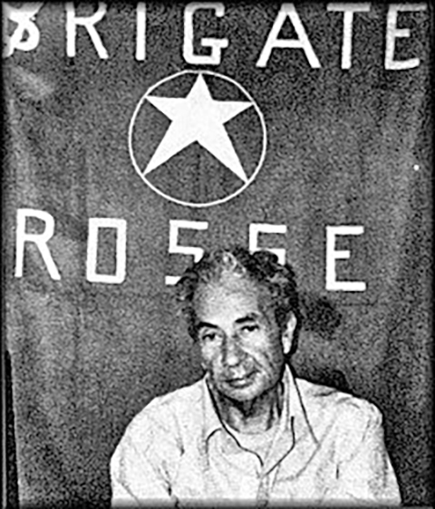 Aldo Moro, gefotografeerd vóór een vlag van zijn ontvoerders, de Brigate Rosse.