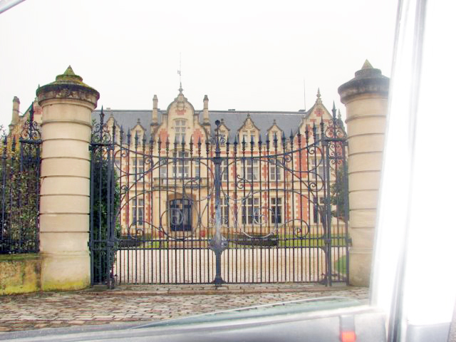 Het château achter een groot hek.
