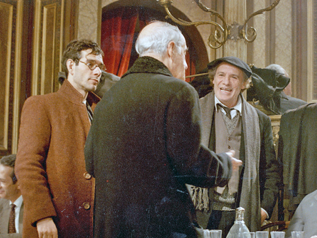 Een moment in de film, waarop de hoofdpersoon naar de jonge dichter staat, een derde persoon op de rug gezien.