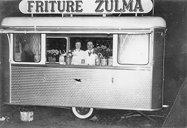 Een frietkot met de tekst 'Friture Zulma' en een man en een vrouw erin.