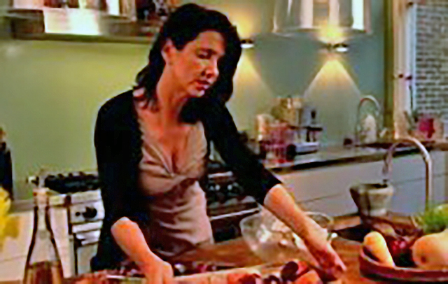 Een foto van Janneke Vreugdeloos in haar keuken, met een decolleté.